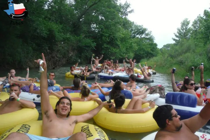 A large group of people cheering for the camera as they float down the river