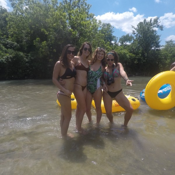 Four girls standing in the river holding beers