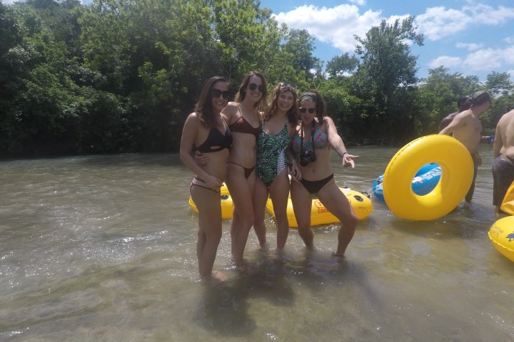 Four girls standing in the river holding beers