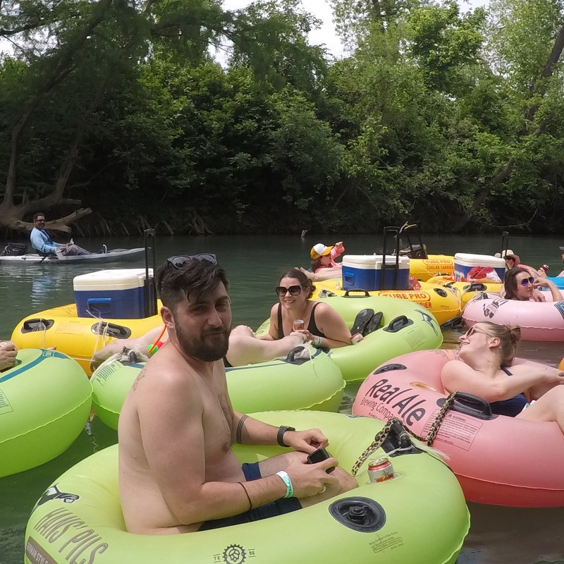 A group of friends floating down the San Marcos River in tubes