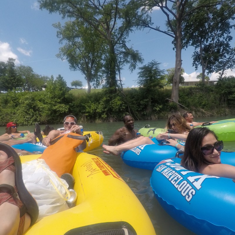 A group of friends floating down the San Marcos River in tubes