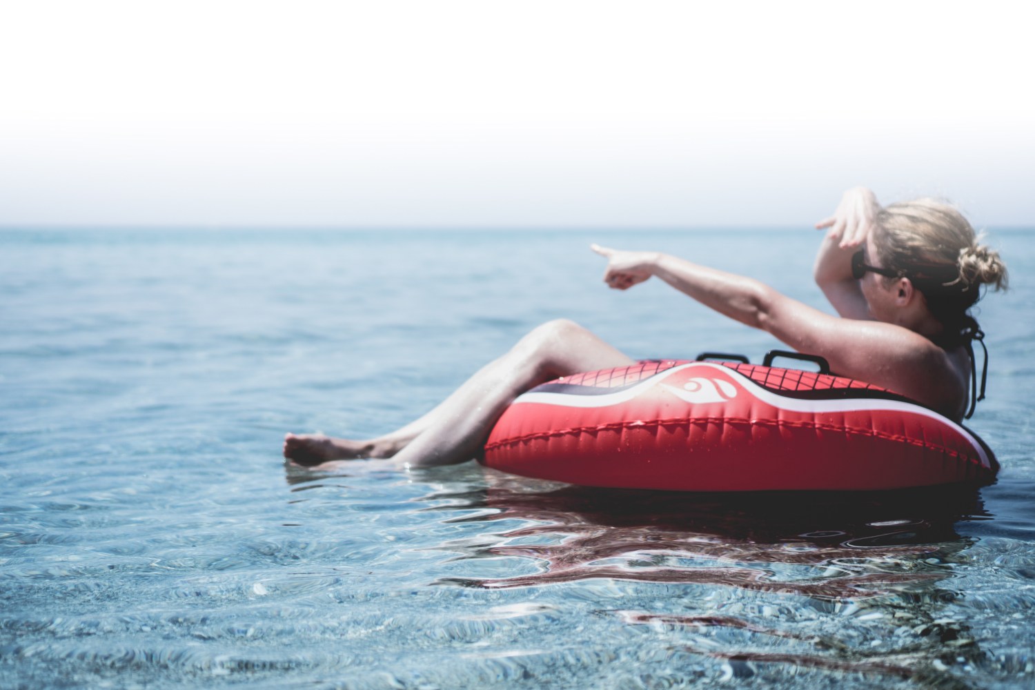 A woman sitting in an inner tube point out into the distance